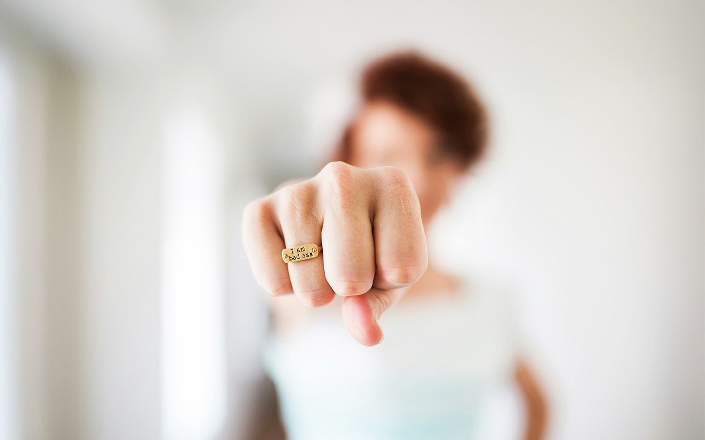 Woman's fist with a gold ring that says "I am bad ass