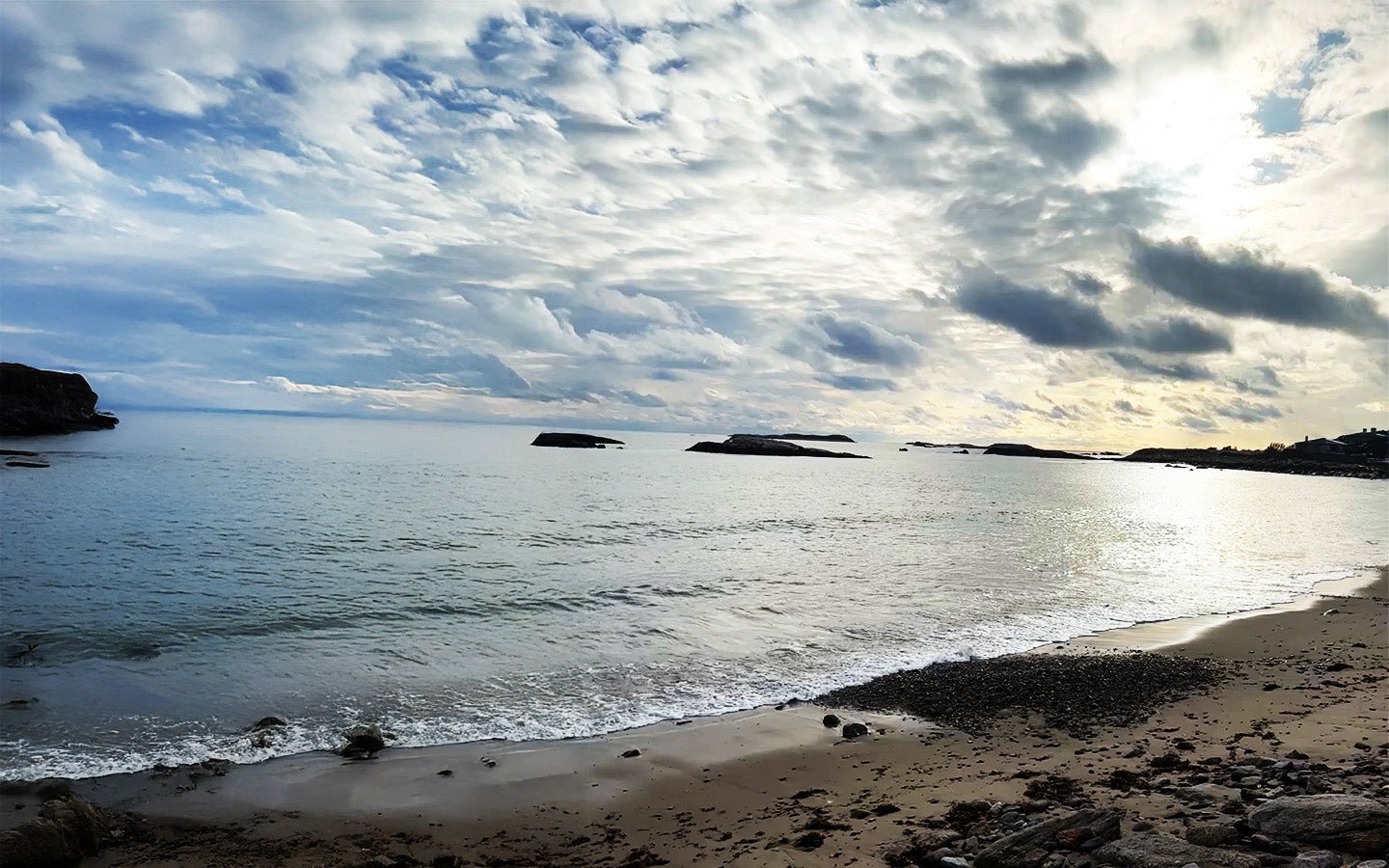 Cloudy sky over a calm sea with a sandy beach and small islands