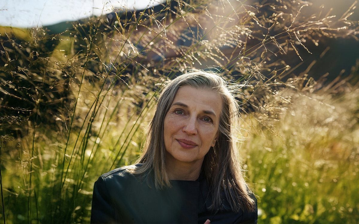 Silver-haired woman seated in sunlit autumn grasses, pausing in quiet reflection — photo by Daria Trofimova