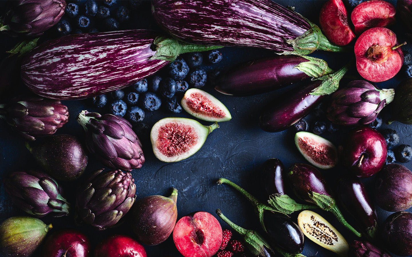Purple vegetables and fruits, including eggplants, artichokes, figs, plums, and blueberries