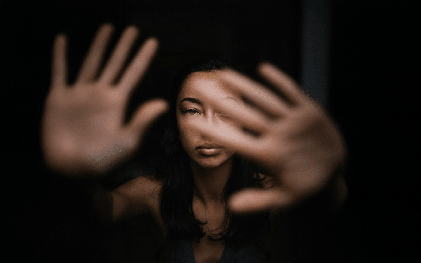 Woman in midlife looking through parted fingers, representing the menopause transition