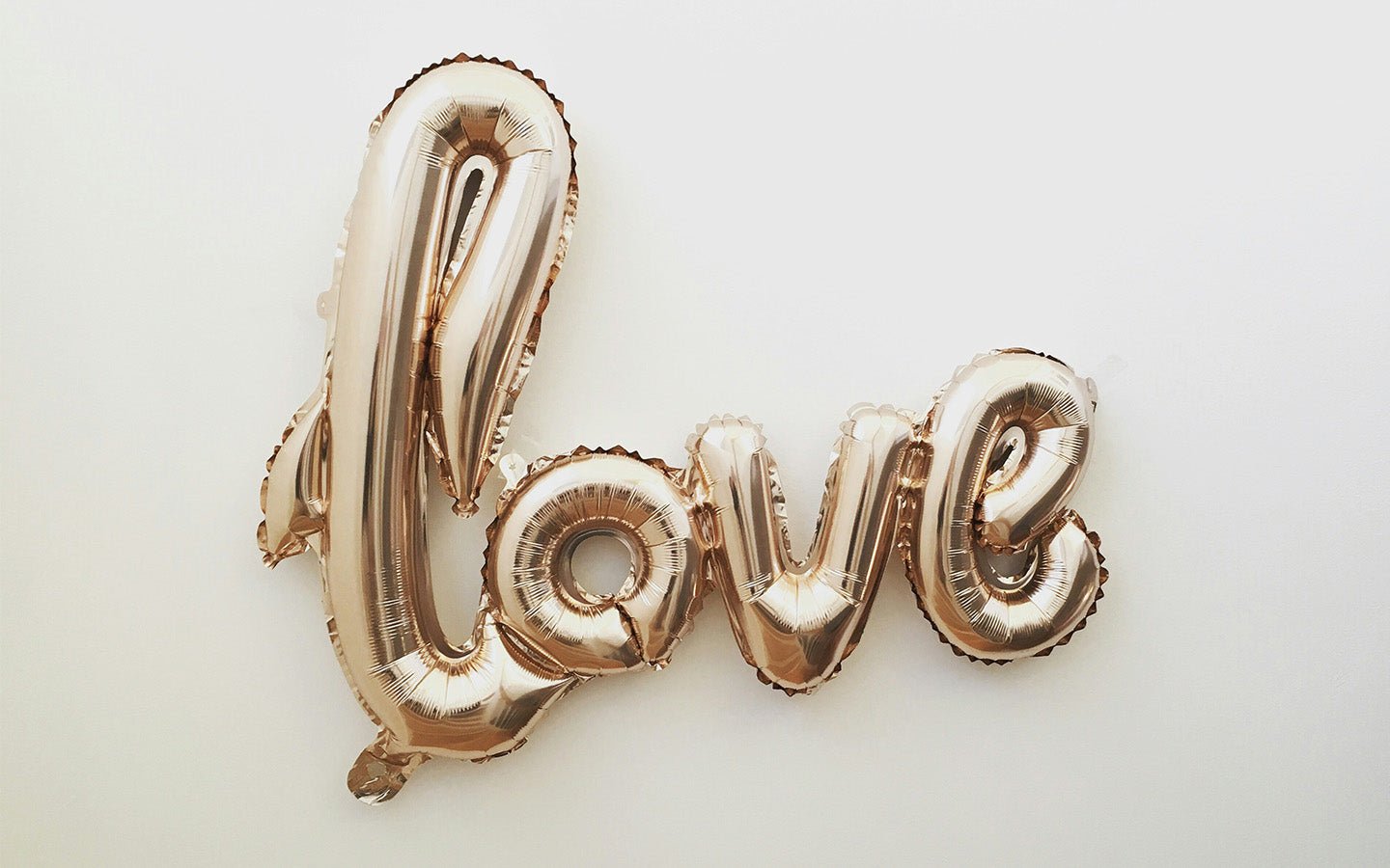 Rose gold "love" balloon letters on a white background