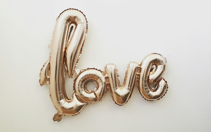 Rose gold "love" balloon letters on a white background