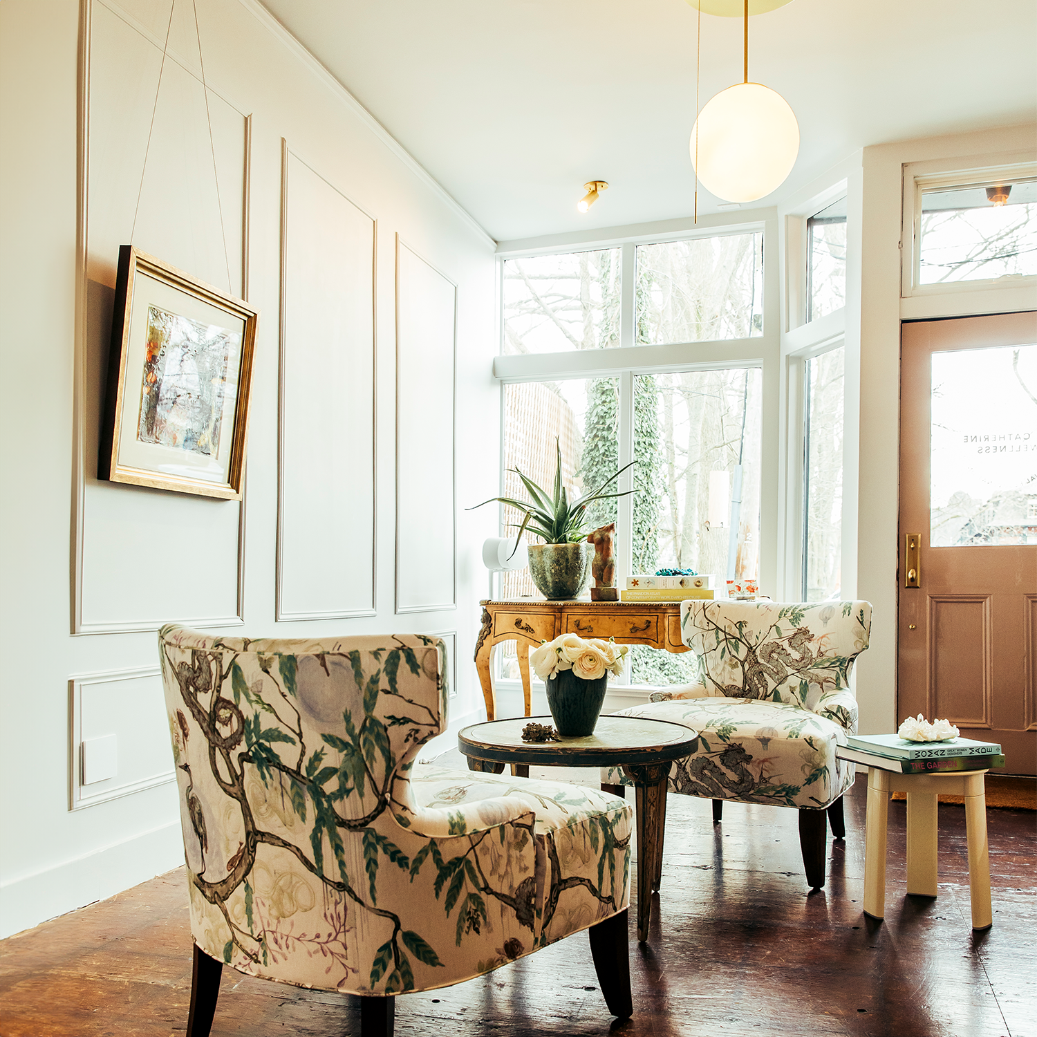 A warm room with two sitting chairs table and flowers
