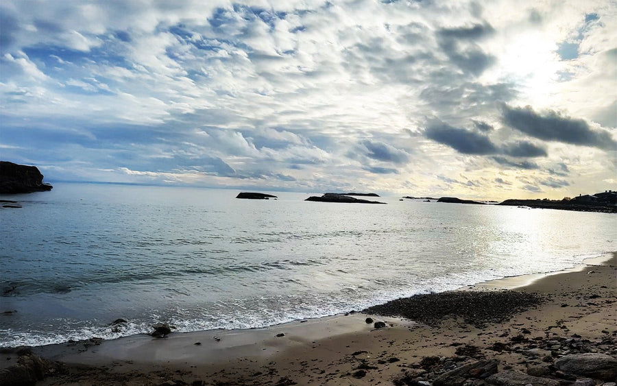 Cloudy sky over a calm sea with a sandy beach and small islands