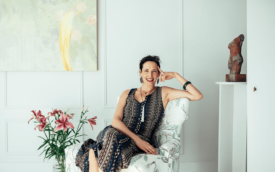 Dr. Catherine laughing in a chair in a bright room with pink lilies and artwork