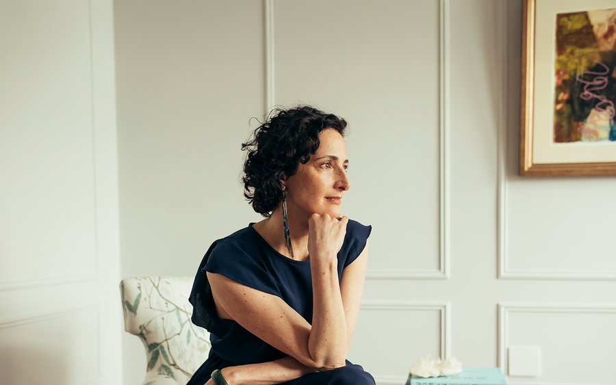 Dr. Catherine gazing toward the window in quiet reflection, chin resting on her hand