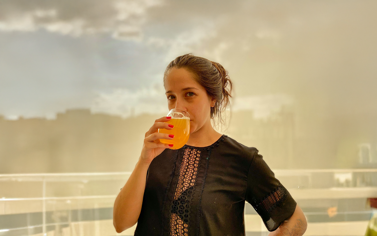 Woman sipping golden kombucha from a glass in natural light
