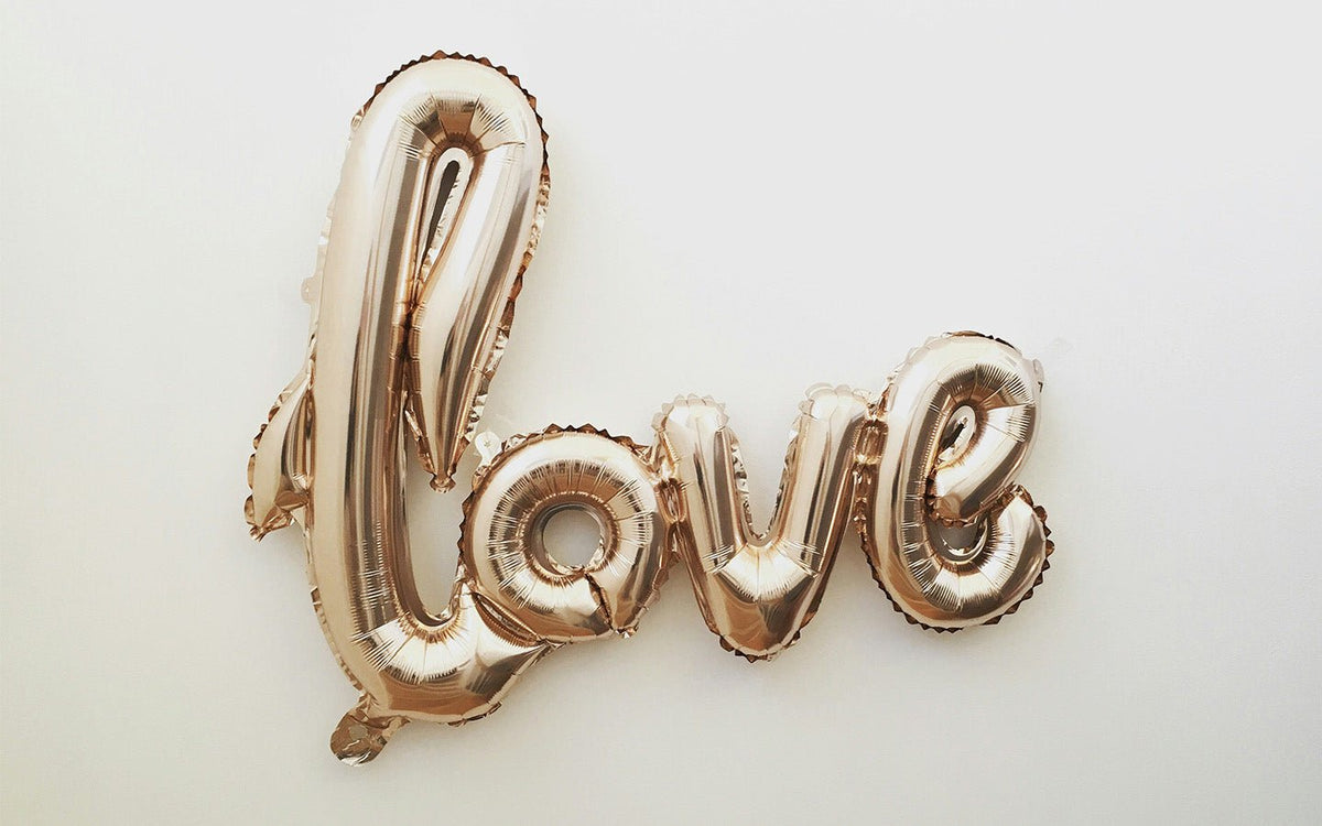 Rose gold "love" balloon letters on a white background